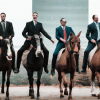 DALL·E 2022-09-29 12.16.40 - photo of 4 businessmen wearing suits on horses in a row, digital art